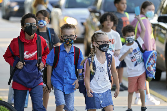 Children arrive at school wearing masks.