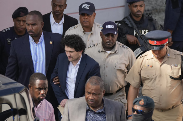 FTX founder Sam Bankman-Fried, centre left, is escorted out of Magistrate Court following a hearing in Nassau, Bahamas.