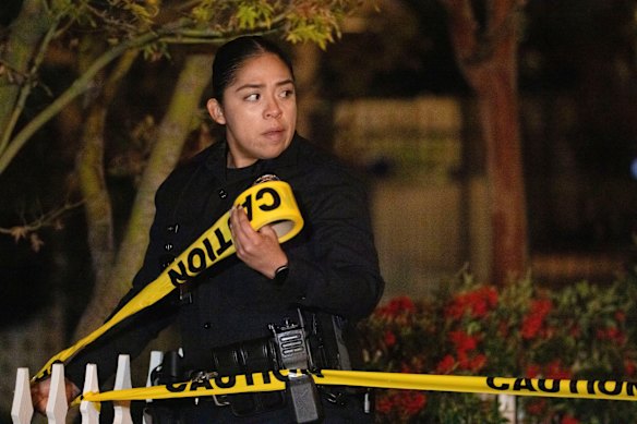 A police officer places tape around the investigation scene near Rob Reiner’s house on Sunday night (Monday afternoon AEDT).