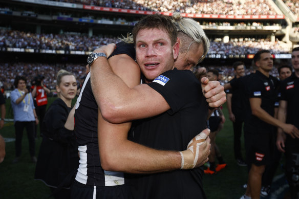 Taylor Adams hugs captain Darcy Moore moments after Collingwood’s premiership win.
