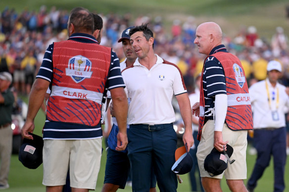 Rory McIlroy talks to a Team USA caddie on the 18th green during the Saturday afternoon fourball matches of the 2023 Ryder Cup in Rome.