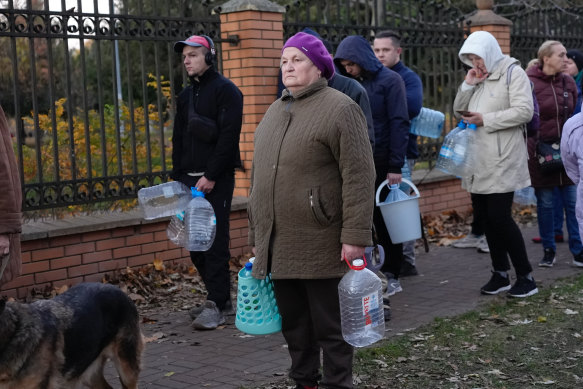 A woman waits to fill containers with water from public water pumps in Kyiv.
