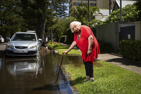 Jane Hester stands outside a huge flow of water on Malvern Avenue, Manly. It has been getting worse for nearly a fortnight.