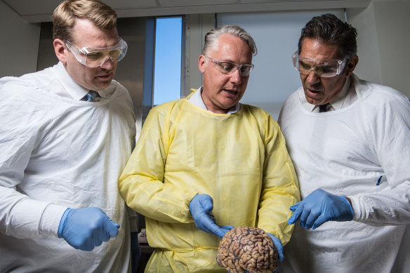 Michael Buckland of RPA, Chris Nowinski from Concussion Legacy Foundation and former rugby player Colin Scotts examine a brain.