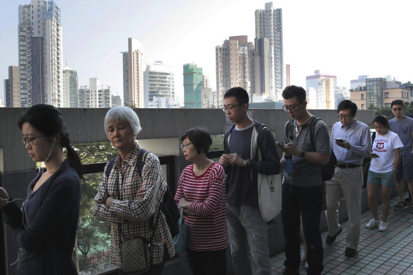 People line up to vote outside of a polling place in Hong Kong on Sunday.