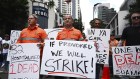 Striking CFMEU members, who work on the Albert St Cross River Rail construction site, hold signs outside the site in Brisbane, April 30, 2024.