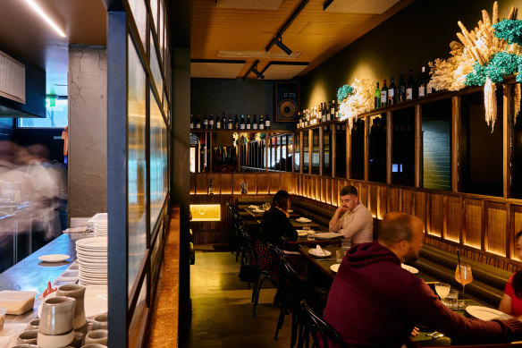 The glass partition alongside the kitchen adds a classic bar vibe.