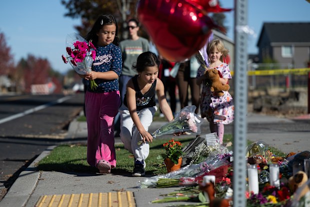 Children place flowers at a makeshift memorial outside Silver Rail Elementary in Bend, Ore., Friday, Oct. 16, 2026, a day after a deadly shooting. (AP Photo/Joe Kline)