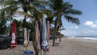 Closed parasols stand on an empty beach in Legian, Bali.