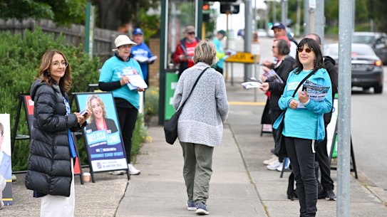 Party volunteers hand out how-to-vote cards at the early voting centre in Camberwell.