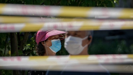 Residents wearing face masks line up behind barricaded tapes for COVID mass testing near a residential area in Beijing.