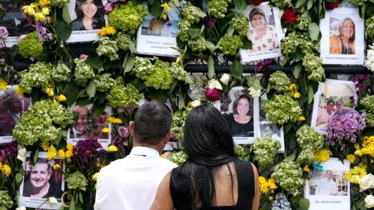 People stand near a makeshift memorial outside St Joseph Catholic Church near the Champlain Towers on Tuesday.
