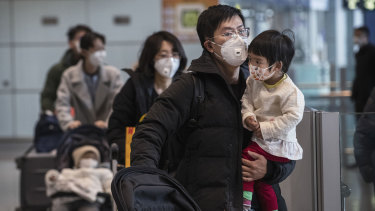 Passengers wear protective masks as they walk in the arrivals area at Beijing Capital Airport.