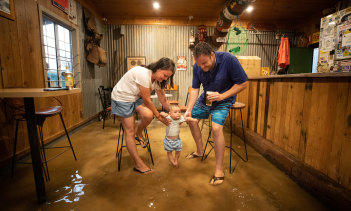 Victorians Teneal and Dan Gray help baby Marlow stomp in the flood water. The family is likely to be stuck in Windorah because of the heavy rain.