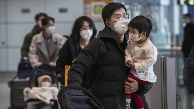 Passengers wear protective masks as they walk in the arrivals area at Beijing Capital Airport.