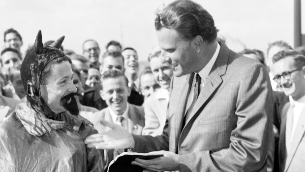 Approachable: Billy Graham speaks to a person dressed as the devil before preaching to students at the University of Sydney in May 1959.