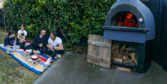 Sandra and Gianluca Bocci with their daughters Chloe (13) Astrid (11) fire up their wood-fire pizza oven in backyard. 