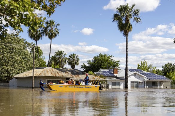 Emergency crews transport people by boat over flooded streets in Forbes, NSW, last week. 