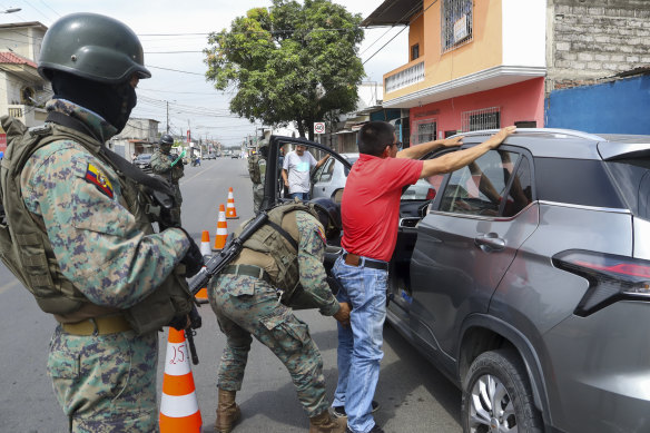 A soldier pats down a driver at a road block in Guayaquil, Ecuador.