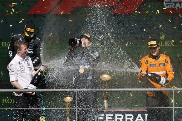 Mercedes driver George Russell of Britain, centre, celebrates on the podium with second place Mercedes driver Lewis Hamilton.