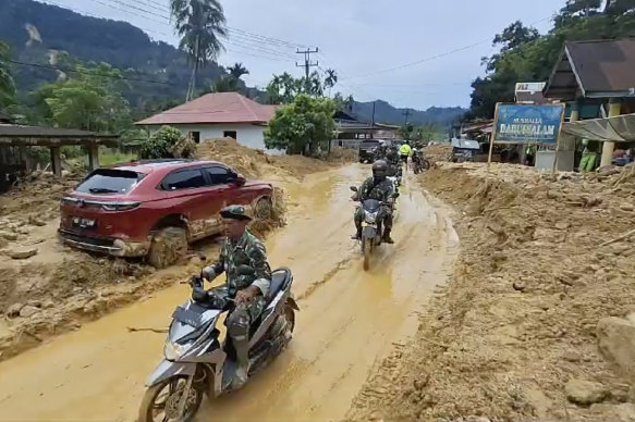 Soldiers ride motor bikes in a village affected by flash flood in Langgai, West Sumatra, Indonesia.