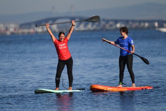 Sharon Bourke (red top) teaching Amber Sarda how to paddleboard at Brighton beach.