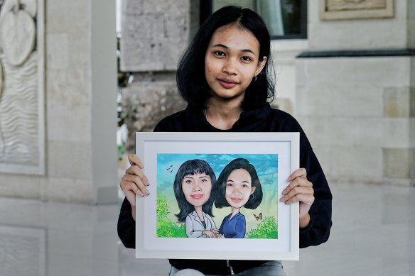 Dinda holds a newly finished artwork in which she was painted alongside her mother.