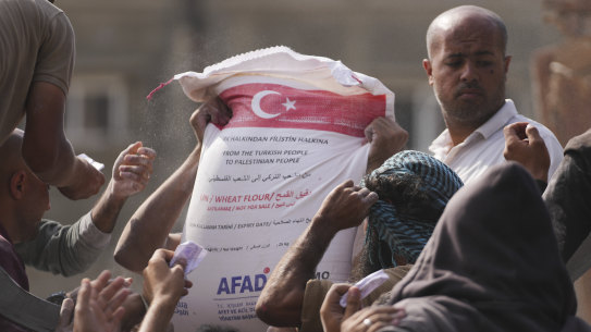 Palestinians gather to receive bags of flour distributed by UNRWA in Deir al-Balah, central Gaza Strip on Saturday.