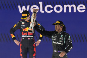 Lewis Hamilton celebrates his win on the podium as Max Verstappen hangs his head.