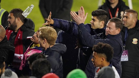 Mariners players and staff react as Hume City supporters throw bottles after the game.