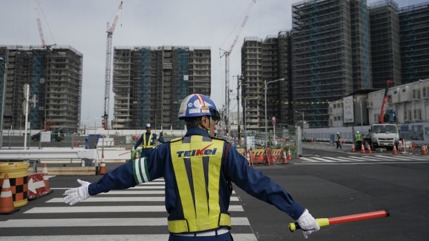 A guard directs traffic at the construction site of the Tokyo Olympic Village last year. Tokyo’s governor is considering the possibility of using the unfinished Olympic Athletes Village as a temporary hospital for coronavirus infected patients. 