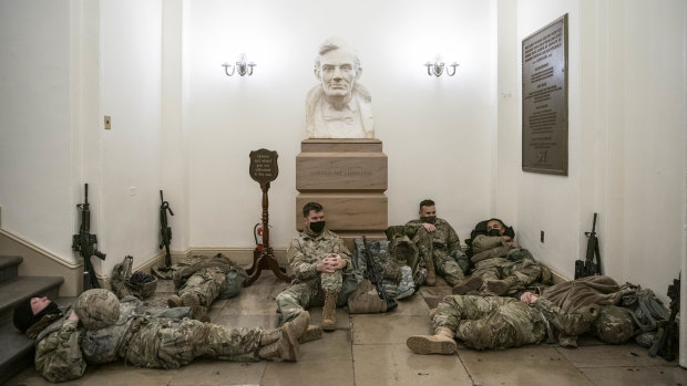 Members of the National Guard rest under a bust of Abraham Lincoln in a hallway of the US Capitol building in Washington ahead of Donald Trump's second impeachment vote.