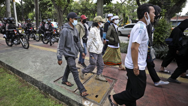 Police officers on motorbikes turn away a group of supporters for cleric Rizieq Shihab at court in Jakarta.