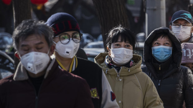 Chinese customers wear protective masks  in Beijing, China, as they line up at a popular dumpling shop.