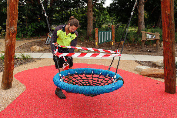 A Willoughby Council worker places hazard tape on outdoor playground equipment at Gore Hill.