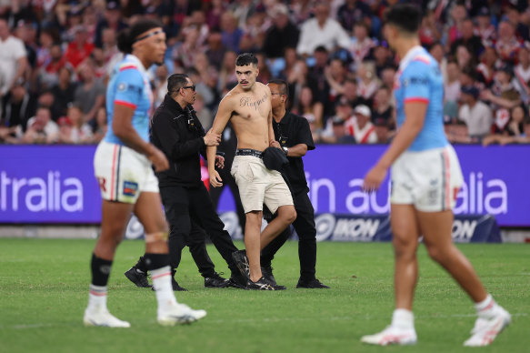 A pitch invader is taken off the field during the Anzac Day clash.