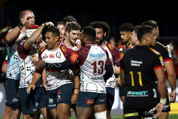 Tate McDermott celebrates with Reds teammates after scoring a try.