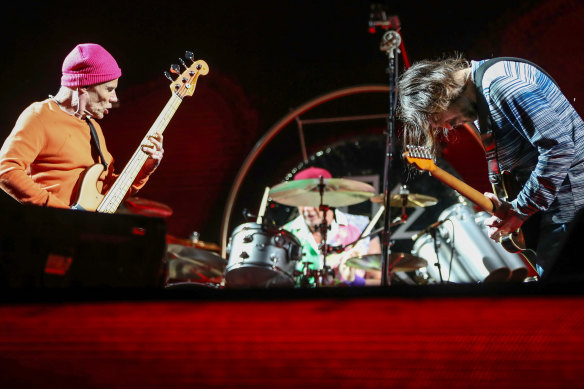 Red Hot Chili Peppers bassist Flea, drummer Chad Smith (face obscured) and guitarist John Frusciante.