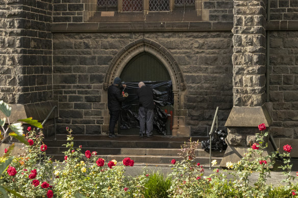 Workers cover graffiti at St Patrick's Cathedral in Melbourne.