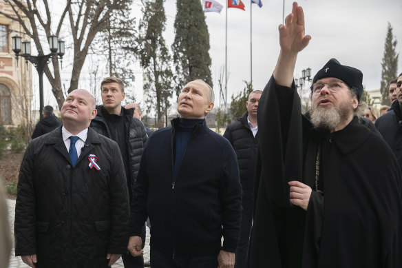 Russian President Vladimir Putin (centre) and Governor of Sevastopol Mikhail Razvozhayev (left) listen to Metropolitan of Pskov and Porkhov Tikhon Shevkunov (right) at the Children’s Art and Aesthetic centre on Saturday.