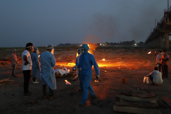 Relatives stand near the funeral pyre of a loved one who died due to COVID-19 in Prayagraj, India.