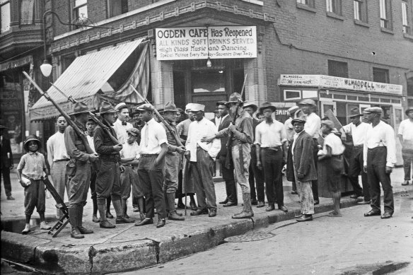 A crowd of men and armed National Guard stand in front of the Ogden Cafe during race riots in Chicago in the Red Summer of 1919. 