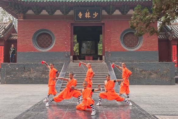 A group of Shaolin kung fu exponents demonstrate their skills in front of the Shaolin Temple in Dengfeng,  Henan Province.