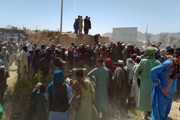 Taliban fighters and Afghans gather around the body of a member of the security forces who was killed in the city of Farah on Wednesday.