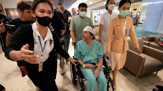 Keith Davis, no centro, é levado embora, impedido de falar com repórteres no Hospital Samitivej Srinakarin em Bangkok, Tailândia, na quinta-feira.