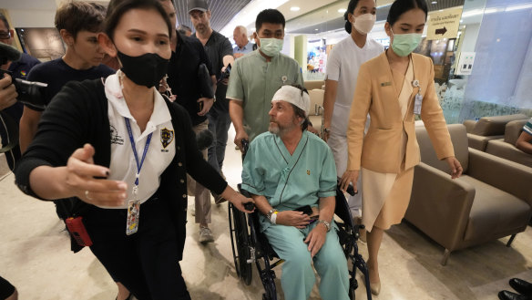 Keith Davis, centre, is whisked away, prevented from talking to reporters at Samitivej Srinakarin Hospital in Bangkok, Thailand, on Thursday.