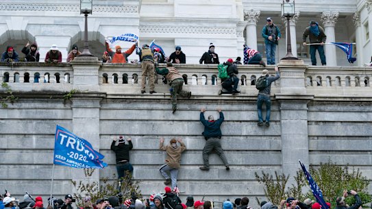 Protesters scale a wall at the US Capitol on January 6 last year.