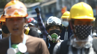 Anti-coup protesters wearing helmets and masks take positions as police gather in Yangon, Myanmar, on Friday.
