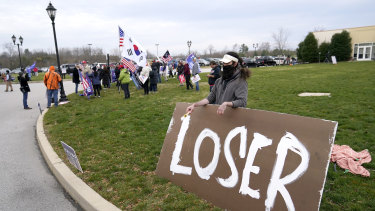 Supporters of President Donald Trump, left, gather as a counter protester holds a sign outside of the Wyndham Hotel where the Pennsylvania State Senate Majority Policy Committee met during the week.