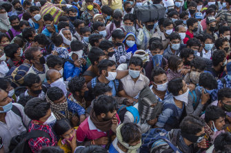 Indian migrant workers crowd to board buses to return to their native villages after a nationwide lockdown was announced.